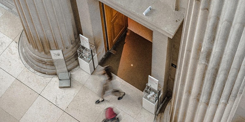 Vom Vogelschau schaut man auf einem Person, die ein Museumgebäude verlässt