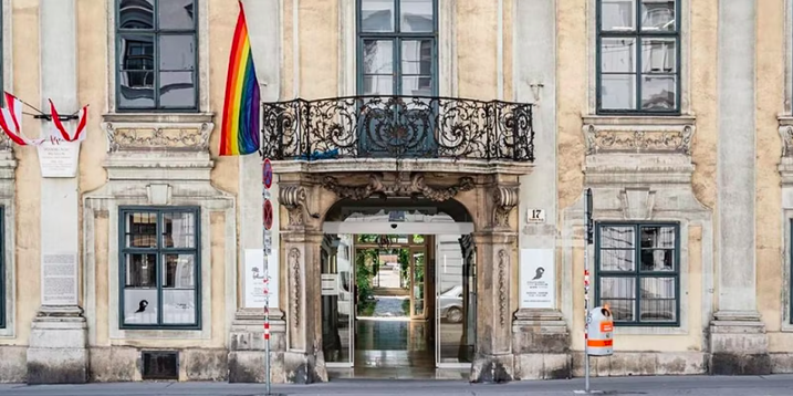 Das Volkskunde Museum, ein barockes Palais, mit einer Regenbogenfahne vor dem Eingang