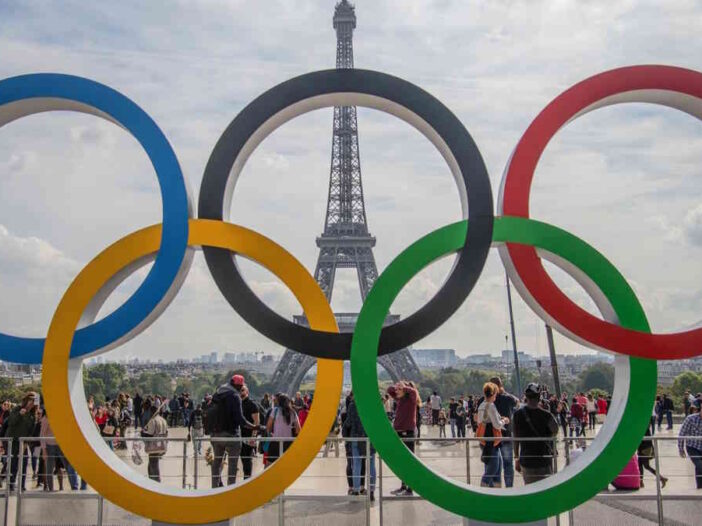 Das Eiffelturm steht hinter den fünf olympsischen Ringe